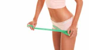 A woman wrapping a tape measure around her thighs