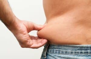 Man pinches extra fat around his belly before GLP-1 weight loss
