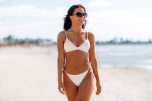 Woman on beach in bikini with slim, toned body from Emsculpt NEO in Navarre